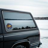 Black SUV with a fish decal on the window, parked on a snowy landscape.